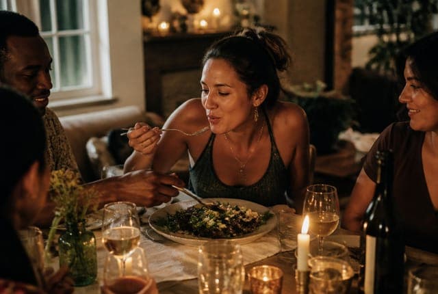 A guest leaning in over a shared plate at a candlelit Tenseats home supper club